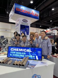 Tandex Operations Manager standing with the Thai distribution team at an industry expo booth displaying boiler and cooling tower water treatment chemicals and scale samples.