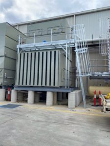 Industrial cooling tower fitted with a metal access platform and ladder, providing safe access for inspection, cleaning, and mechanical servicing.