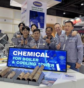 Tandex Operations Manager standing with the Thai distribution team at an industry expo booth displaying boiler and cooling tower water treatment chemicals and scale samples.