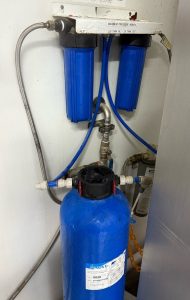Demineralisation unit consisting of blue pre-filter housings, connected pipework, and a blue resin vessel used for producing demineralised water in an industrial setting.