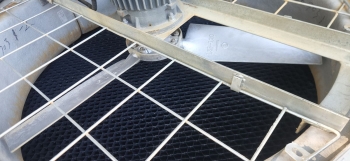 Top view inside a cooling tower showing drift eliminators positioned below the fan and metal safety grating, illustrating internal structure and air flow components.