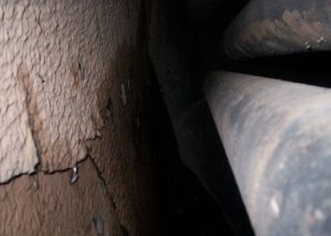 Internal view of a boiler drum showing heavy, cracked mineral scale covering the metal surface prior to treatment, indicating long-term poor boiler water management and significant deposit build-up.