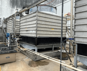 Industrial cooling towers connected as part of a system with balance lines and pipework linking the towers to the internal plant and circulation system.