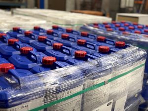 Rows of blue Tandex chemical drums with red caps, palletised and wrapped in plastic for export from the factory.