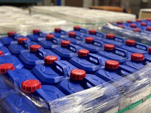 Blue plastic chemical drums with red caps stacked on pallets and wrapped in plastic, ready for export from the Tandex warehouse.