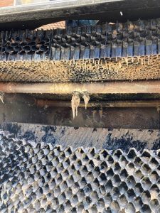 Heavily fouled cooling tower distribution header, drift eliminators, and fill pack covered in biological growth and deposits prior to a cooling tower super clean.